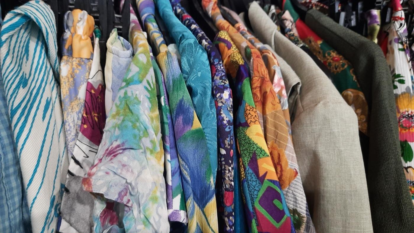 Colourful patterned pre-loved garments hanging closely on a clothing rack