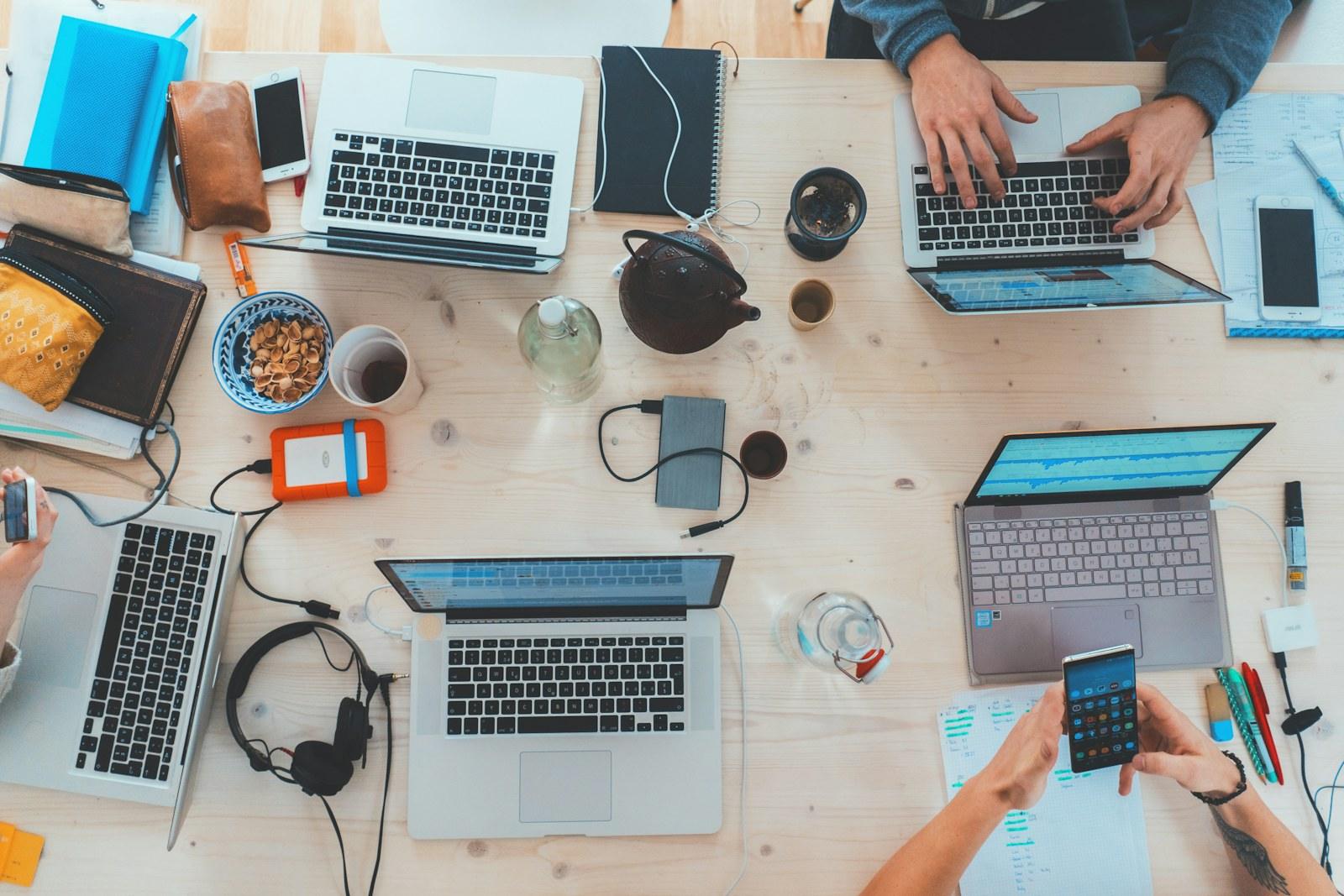 People collaborating around laptops at a shared work table